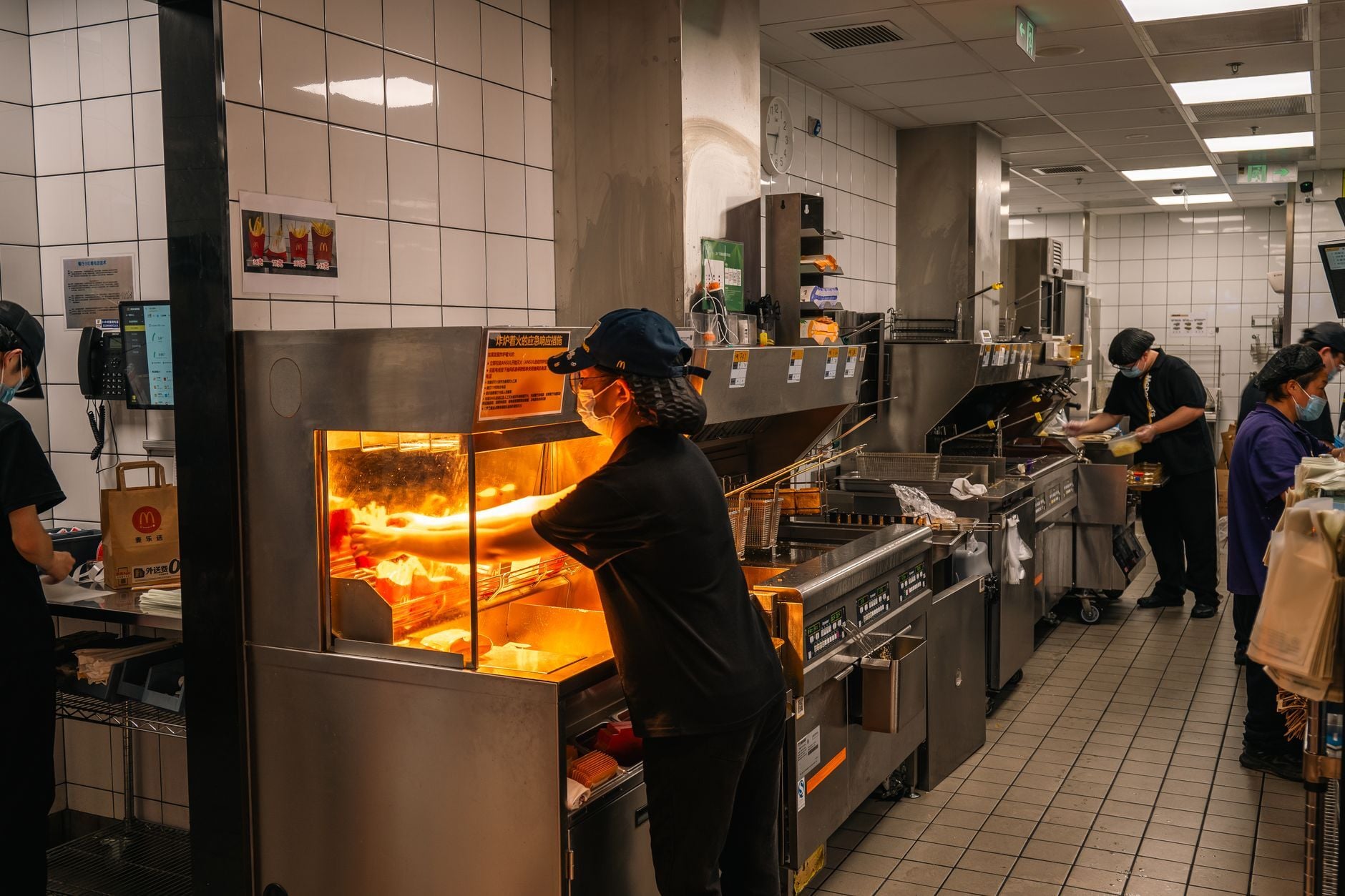 Inside view of a bustling fast-food kitchen in Nanjing, China with staff preparing orders. Photo by Cheng Shi Song on Pexels