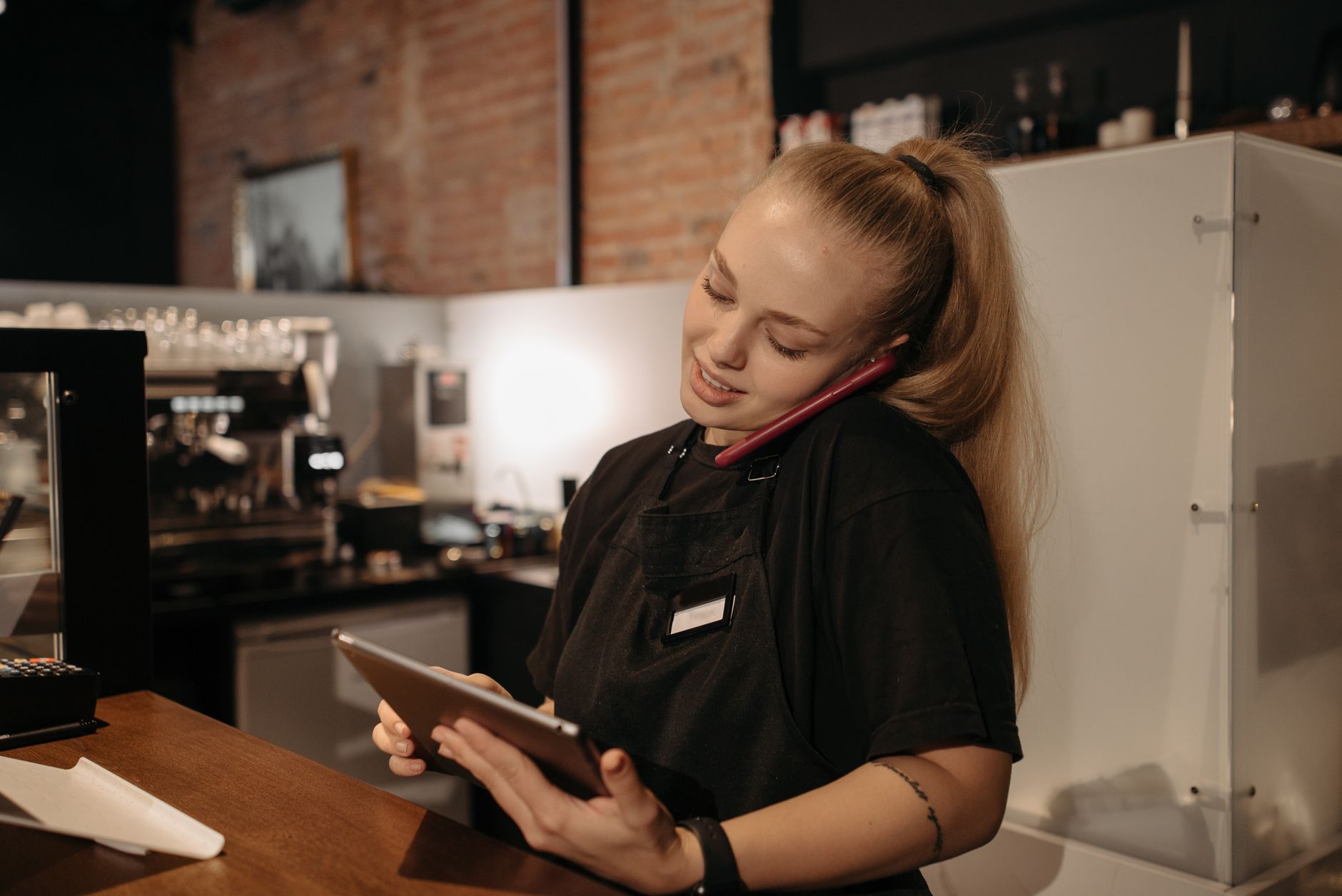 Young woman in café multitasking with a tablet and phone at the counter. Photo by Pavel Danilyuk on Pexels