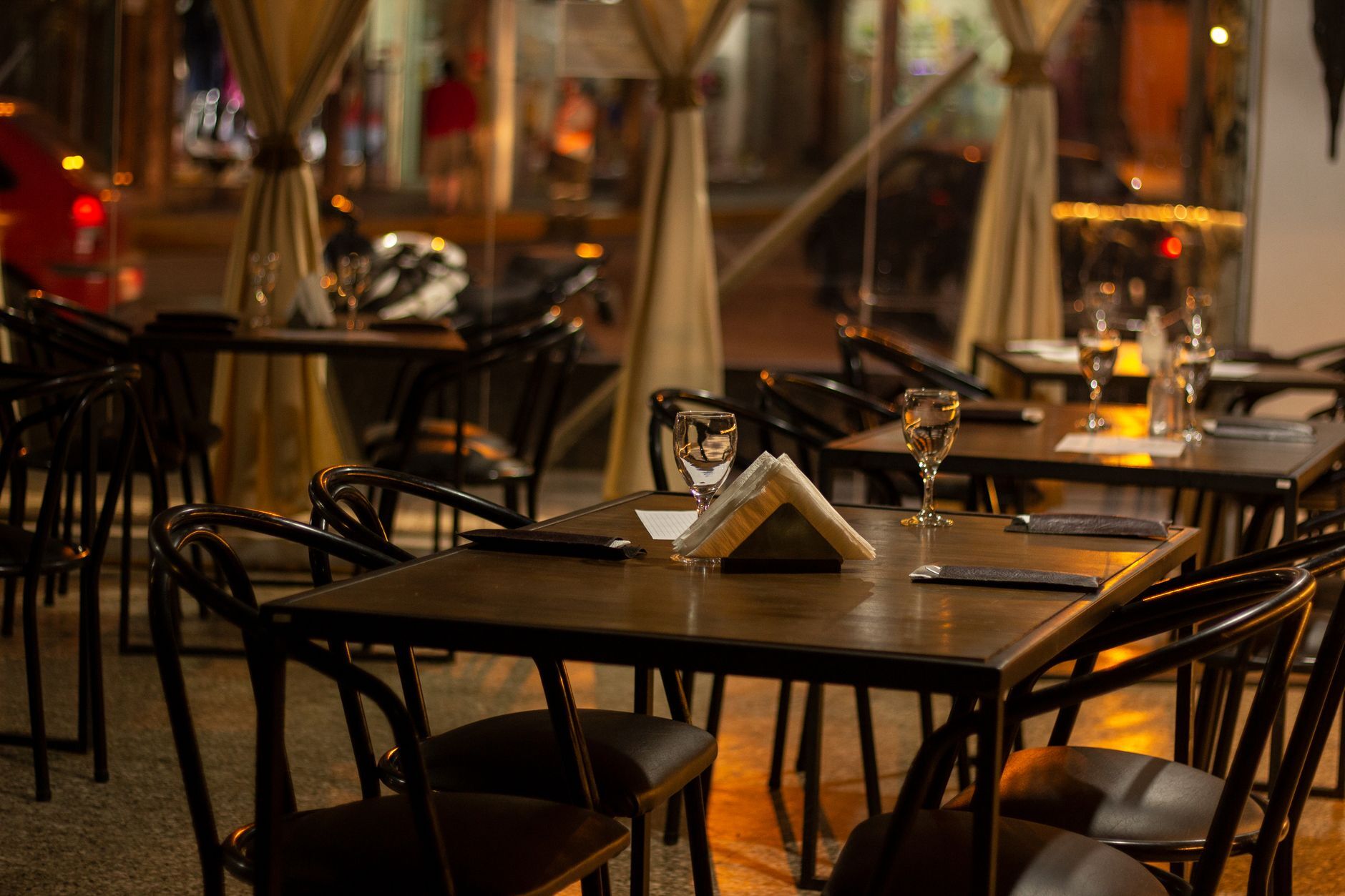 Warmly lit restaurant interior with set tables and wineglasses. Photo by Hernán Santarelli on Pexels