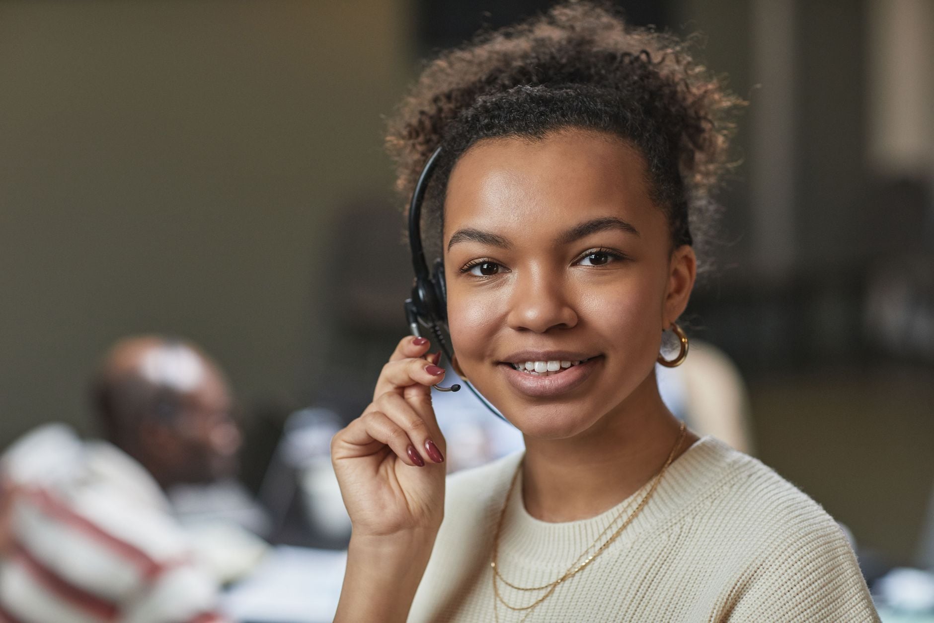Friendly woman in a call center environment, wearing a headset and smiling. Photo by Jep Gambardella on Pexels