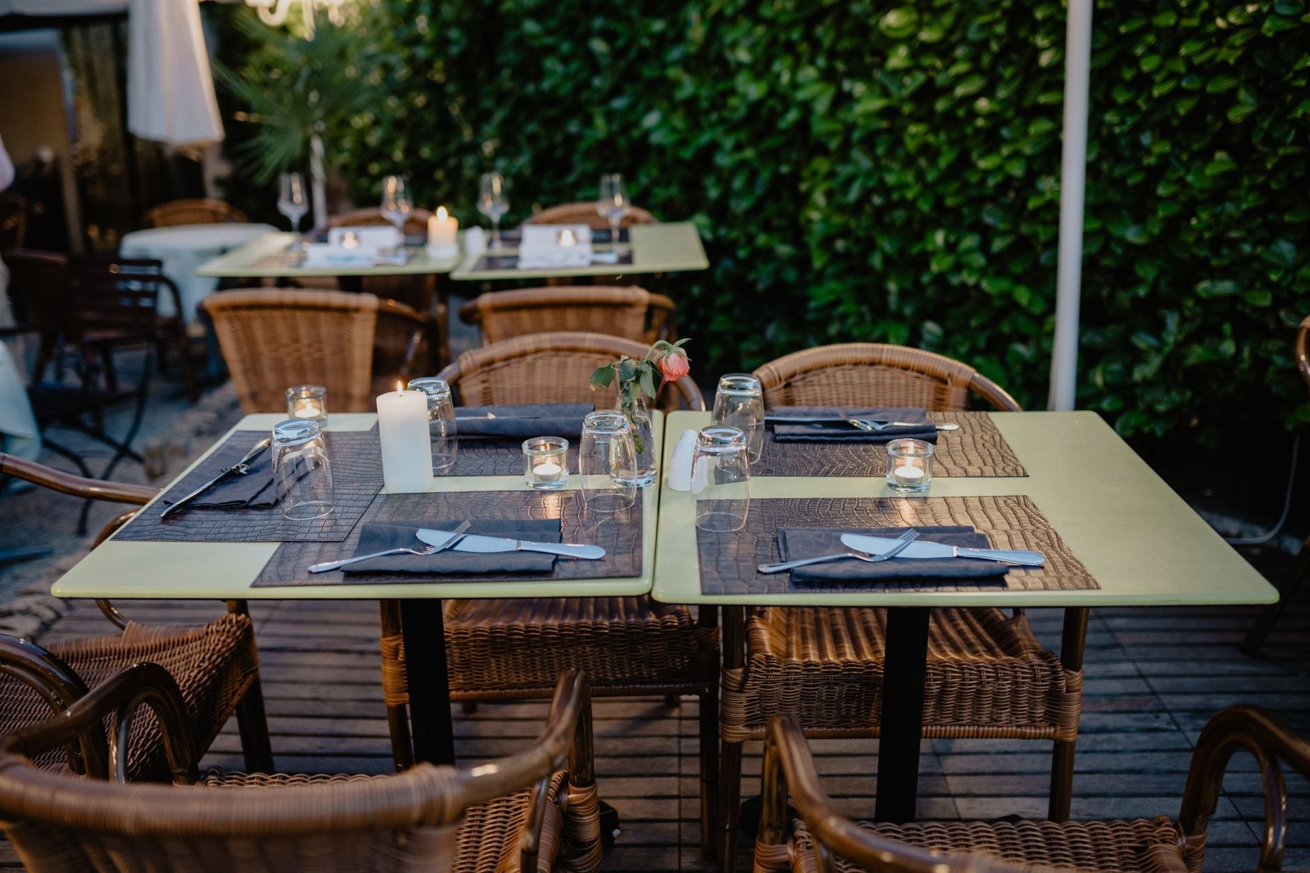 Intimate outdoor dining setting with wicker chairs and candlelit tables on a charming terrace. Photo by Boris Ivas on Pexels