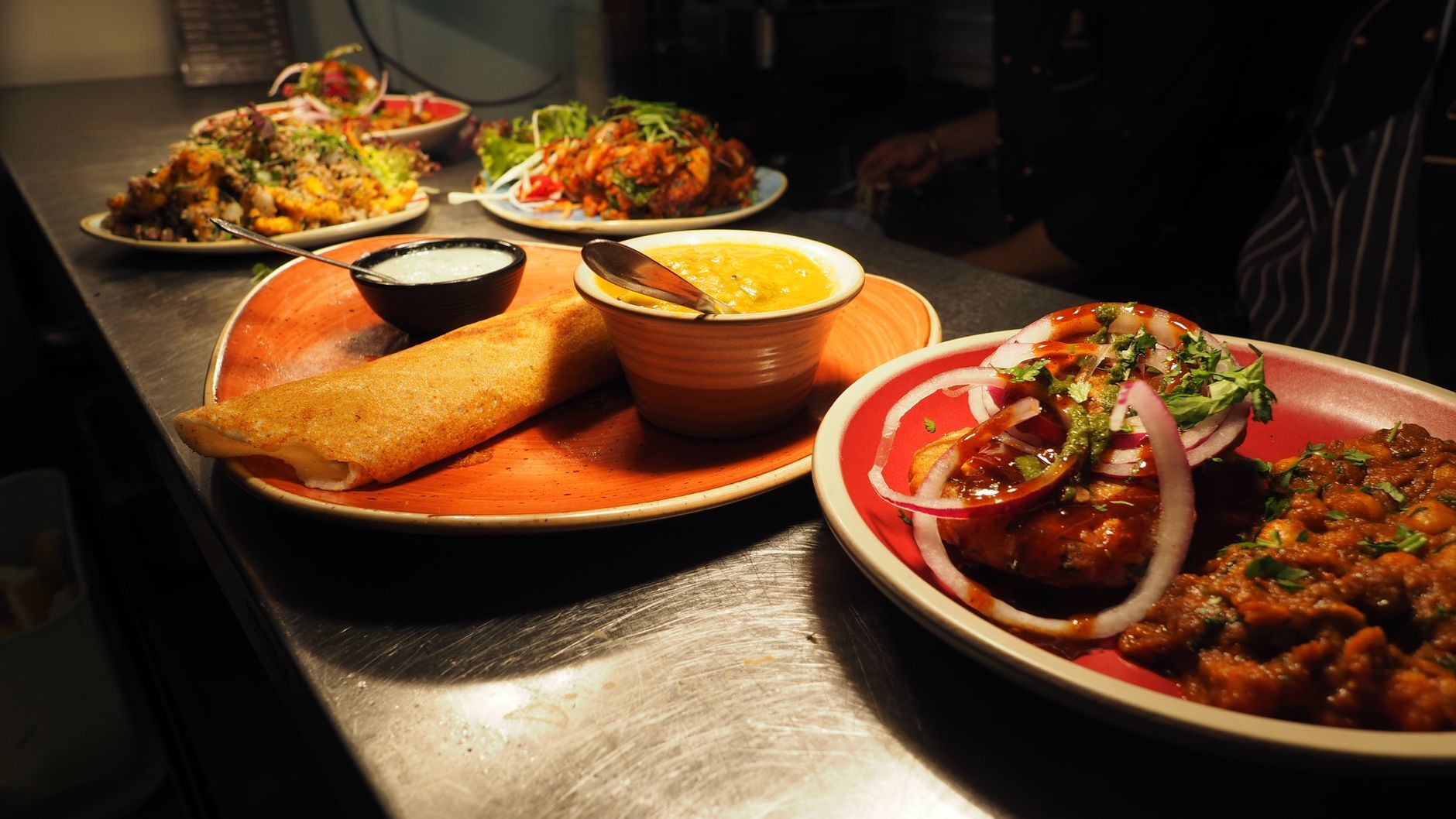 A spread of Indian dishes including dosa, curry, and chutney served on vibrant plates. Photo by Chan Walrus on Pexels