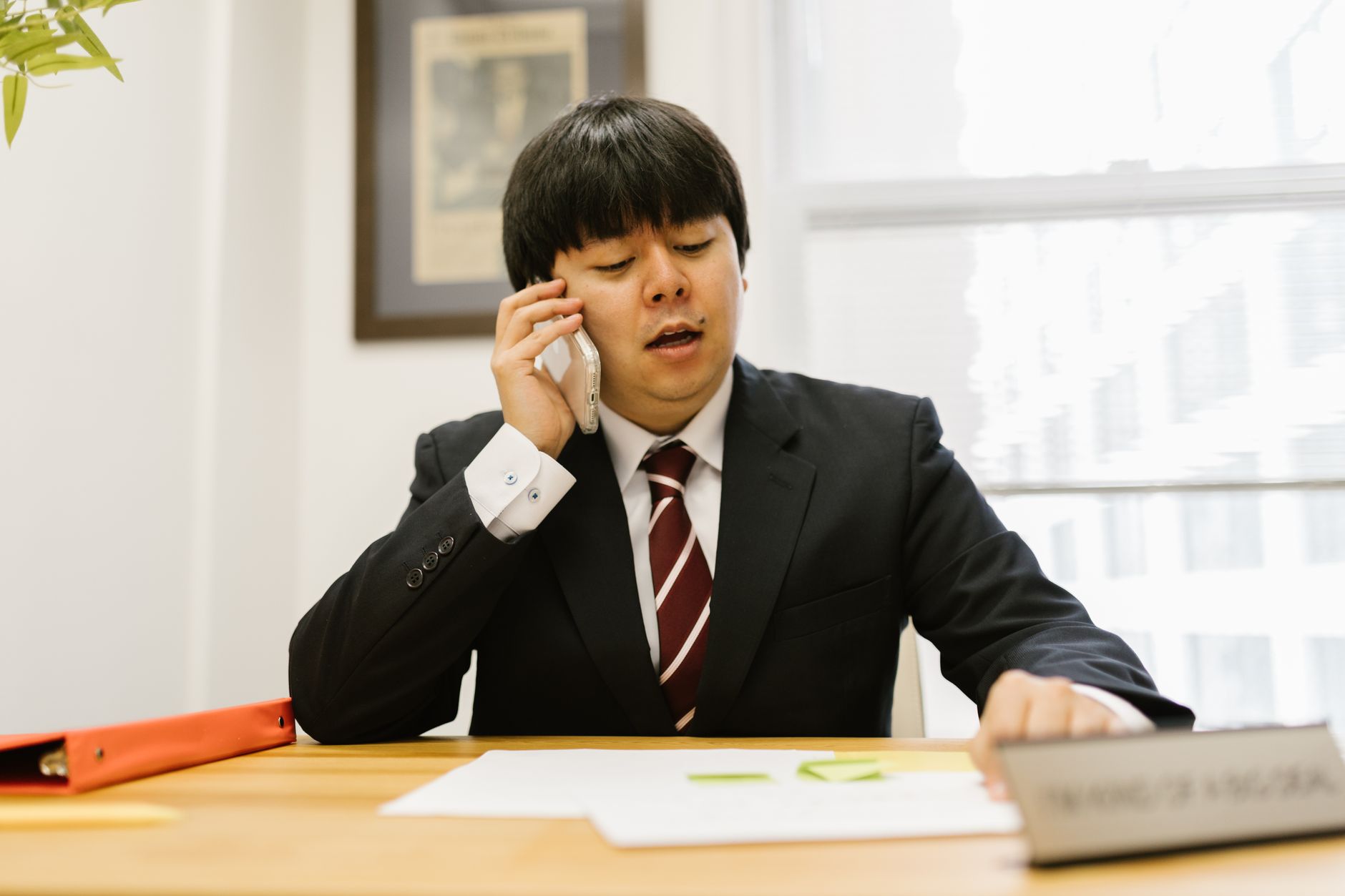 Asian businessman in black suit talking on phone at desk in office Photo by RDNE Stock project on Pexels